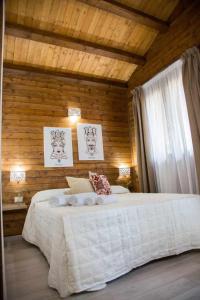 - une chambre avec un grand lit blanc et des murs en bois dans l'établissement Resort con piscina e vicino al mare, à San Cono