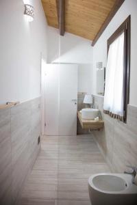La salle de bains blanche est pourvue d'un lavabo et d'un miroir. dans l'établissement Resort con piscina e vicino al mare, à San Cono