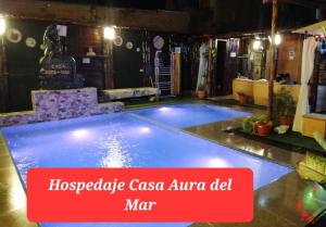 a large swimming pool in a room with a red sign at Casa Aura Del Mar in Máncora