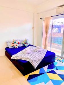 a bedroom with a blue bed with a colorful floor at เดอะซันเซ็ท บางแสน in Chon Buri
