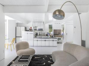 a white kitchen with two chairs and a table at Former Steve McQueen’s home in Palm Springs