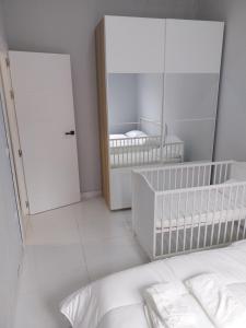a white bedroom with a crib and a mirror at La Iniciativa 2: La luz y El camino in Madrid