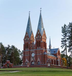 a large building with a clock tower on a field at Dzērves apartamenti in Nastrova