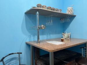 una mesa con una pared azul con un estante con gafas en Dzērves apartamenti, en Nastrova