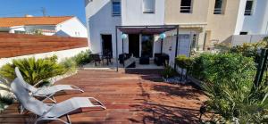 un patio con 2 sillas blancas y un edificio en Maison 3 chambres quartier Croix de Vie, en Saint Gilles Croix de vie