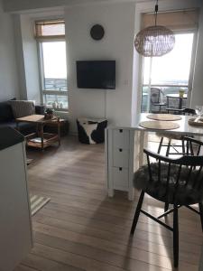 cocina y sala de estar con mesa y sillas en Hyggelig lejlighed med havudsigt - tæt på strand, en Tranekær