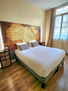 a bedroom with a large white bed with a map on the wall at Logis Hôtel Lafayette Rochefort France in Rochefort