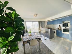 une cuisine avec des armoires bleues, une table et une plante dans l'établissement Splendide roof top au pied de la grande plage, à Saint-Gilles-Croix-de-Vie