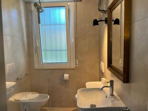 a bathroom with a sink and a toilet and a window at Villa Giorgio 1 relax in pineta in Bibione
