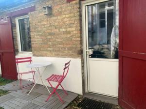 2 Stühle und ein Tisch auf einer Terrasse mit einer Tür in der Unterkunft Tiny house avec terrasse in Versailles