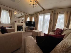 a living room with a couch and a television at Lapwing 60, Scratby - California Cliffs, Parkdean, sleeps 6, bed linen and towels included, no pets in Great Yarmouth
