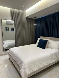een slaapkamer met een groot wit bed en een blauw kussen bij Downtown Luxury Apt Naco: 2br 2ba in Santo Domingo