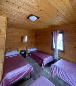 a room with three beds in a log cabin at Thethi Paradise Hotel & Restaurant in Theth