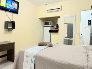 um quarto com uma cama e uma televisão na parede em Capim dourado privativo a minutos do aeroporto em Palmas