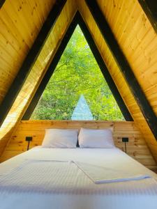 a bed in a wooden room with a large window at A-Frame Rest-Art in Batumi