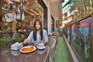 a woman sitting at a table with a plate of fruit at Lakhey Hotel in Kathmandu