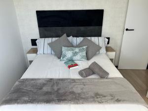 a bed with three pillows and a book on it at La Terraza del Àtico con parking incluido in Vigo