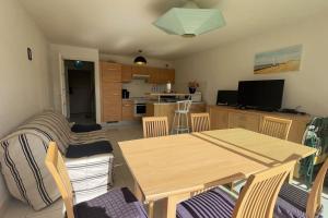 a living room with a table and chairs and a kitchen at Appartement Anaïs au calme à quelques pas de la mer avec wifi in Merlimont