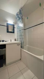 a bathroom with a tub and a sink and a shower at Appartement Anaïs au calme à quelques pas de la mer avec wifi in Merlimont