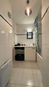 a white bathroom with a sink and a mirror at Appartement Anaïs au calme à quelques pas de la mer avec wifi in Merlimont