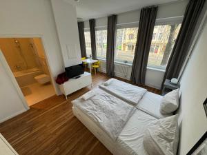Berlinhome Apartment Steglitz في برلين: غرفة نوم بسرير أبيض في غرفة بها نوافذ