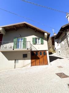 een huis met een houten deur en een balkon bij La casa di Prit in Roccasparvera