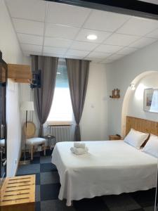 1 dormitorio con cama blanca y ventana en Hôtel Le National, en Saint-Étienne