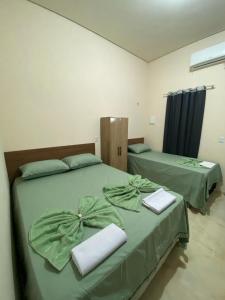 two beds in a room with green sheets at Pousada Lençóis Encantados - Centro de Barreirinhas in Barreirinhas