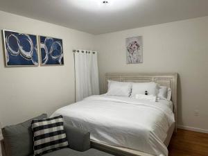een slaapkamer met een wit bed en een stoel bij Deluxe 3 Bedroom EWR airport home in Elizabeth