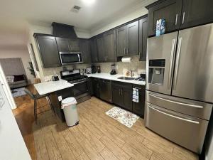 een keuken met zwarte kasten en een roestvrijstalen koelkast bij Deluxe 3 Bedroom EWR airport home in Elizabeth