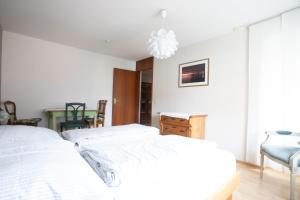 a white bedroom with a bed and a table at Storchennest - Großzügiges sonniges Wohlfühl-Apartment mit traumhafter Terrasse in Tettnang