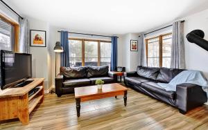 a living room with black leather furniture and a flat screen tv at 16 Chemin Alpin in Stoneham