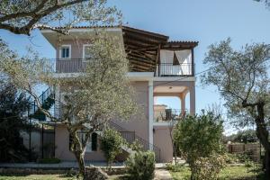a house with a balcony and trees in front of it at Santa Maroma Rooms & Houses in Vasilikos