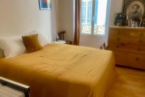 een slaapkamer met een geel bed, een dressoir en een raam bij Cozy apartment in a lively Nice district in Nice
