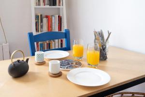 una mesa de madera con platos y vasos de zumo de naranja en Nice apartment in the heart of Paris - Welkeys en París