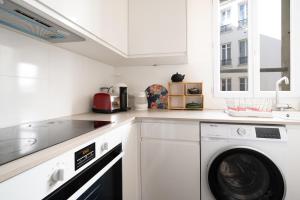 Una cocina blanca con lavadora y secadora. en Nice apartment in the heart of Paris - Welkeys en París
