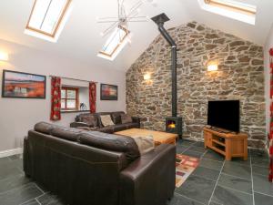 a living room with couches and a stone fireplace at The Old Dairy in Pwllheli