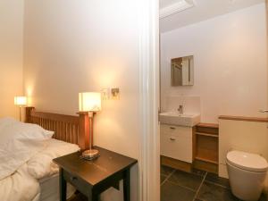 a bedroom with a bed and a toilet and a sink at The Old Dairy in Pwllheli +25 photos