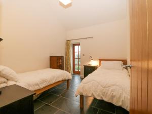 a bedroom with two beds and a table with a lamp at The Old Dairy in Pwllheli