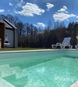 a swimming pool with a chair sitting next to a house at Leśna Polana Domki in Okuninka