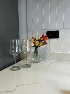 two wine glasses and a vase with flowers on a counter at Mamitas House! Mini Suit Privada Junto al Metro de Quito in Quito