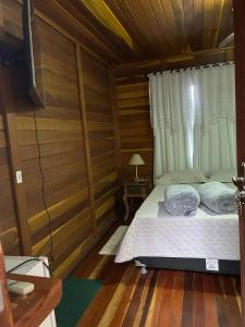 a bedroom with a bed in a wooden room at Chalé Ipê Branco in Pedra Azul