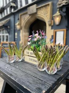 a wooden table with four glass vases filled with flowers at The Royal Oak in Evesham