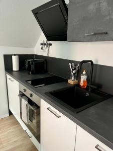 a kitchen with a sink and a black counter top at Flores City Center Studio - Easy Self-Check-IN in Graz +12 photos