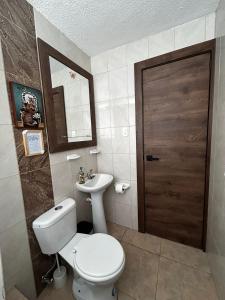 a bathroom with a toilet and a sink and a door at Mamitas House! Mini Suit Privada Junto al Metro de Quito in Quito