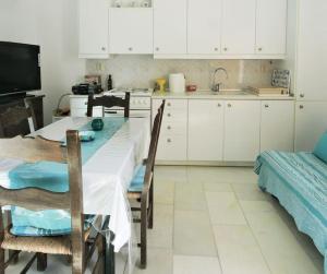 een keuken met een tafel en stoelen en witte kasten bij Teal Blue Serenity in Agiassos
