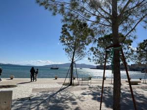 a group of people standing on a beach near the water at Comfort Apartments Promenade in Sarandë