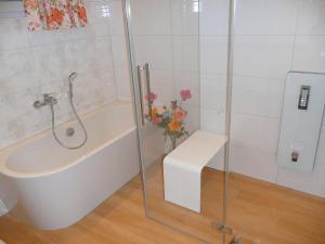 baño con bañera y un jarrón de flores en NEU! Ferienwohnung mit Dampfdusche, en Wertach