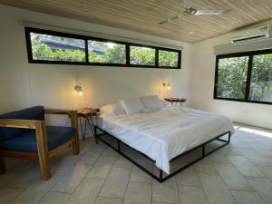 1 dormitorio con 1 cama, 1 silla y ventanas en Posada Sirena, en Uvita