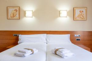 una camera da letto con due asciugamani su un letto bianco di Hotel Zaravencia Plaza Mayor by InsideHome a Toro